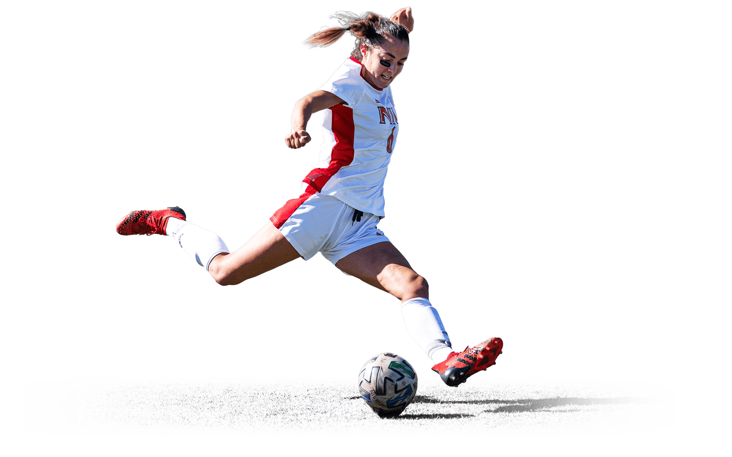 Women's soccer player kicking the ball