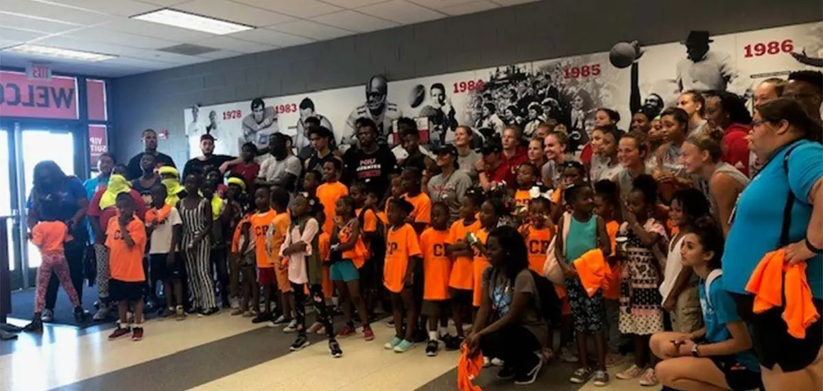 Student-athletes posing with a group of children
